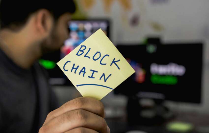 Man holding a post-it note with blockchin written on it