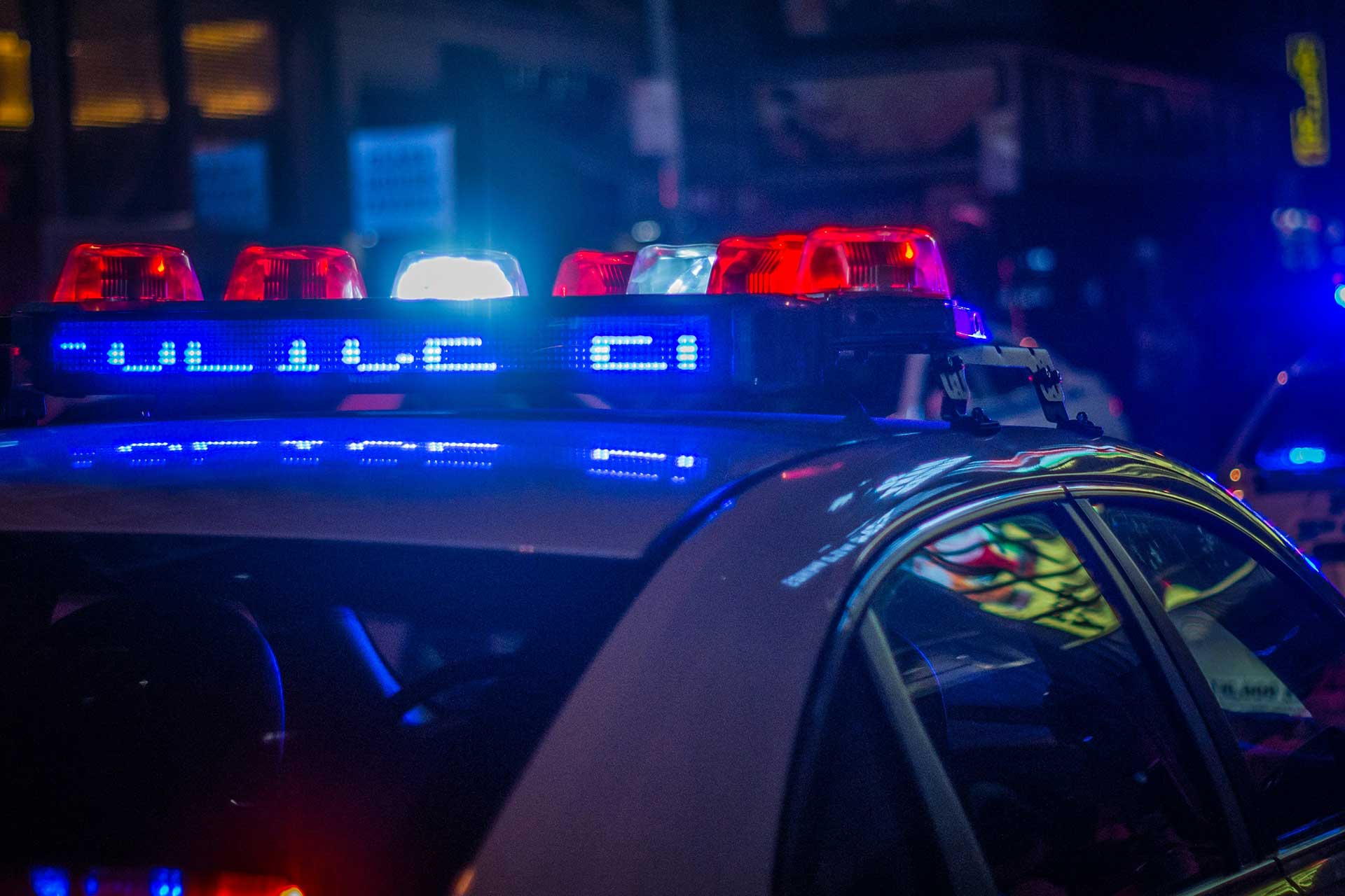 Police lights illuminating downtown Cincinnati at night, representing the city’s evolving public safety strategy.
