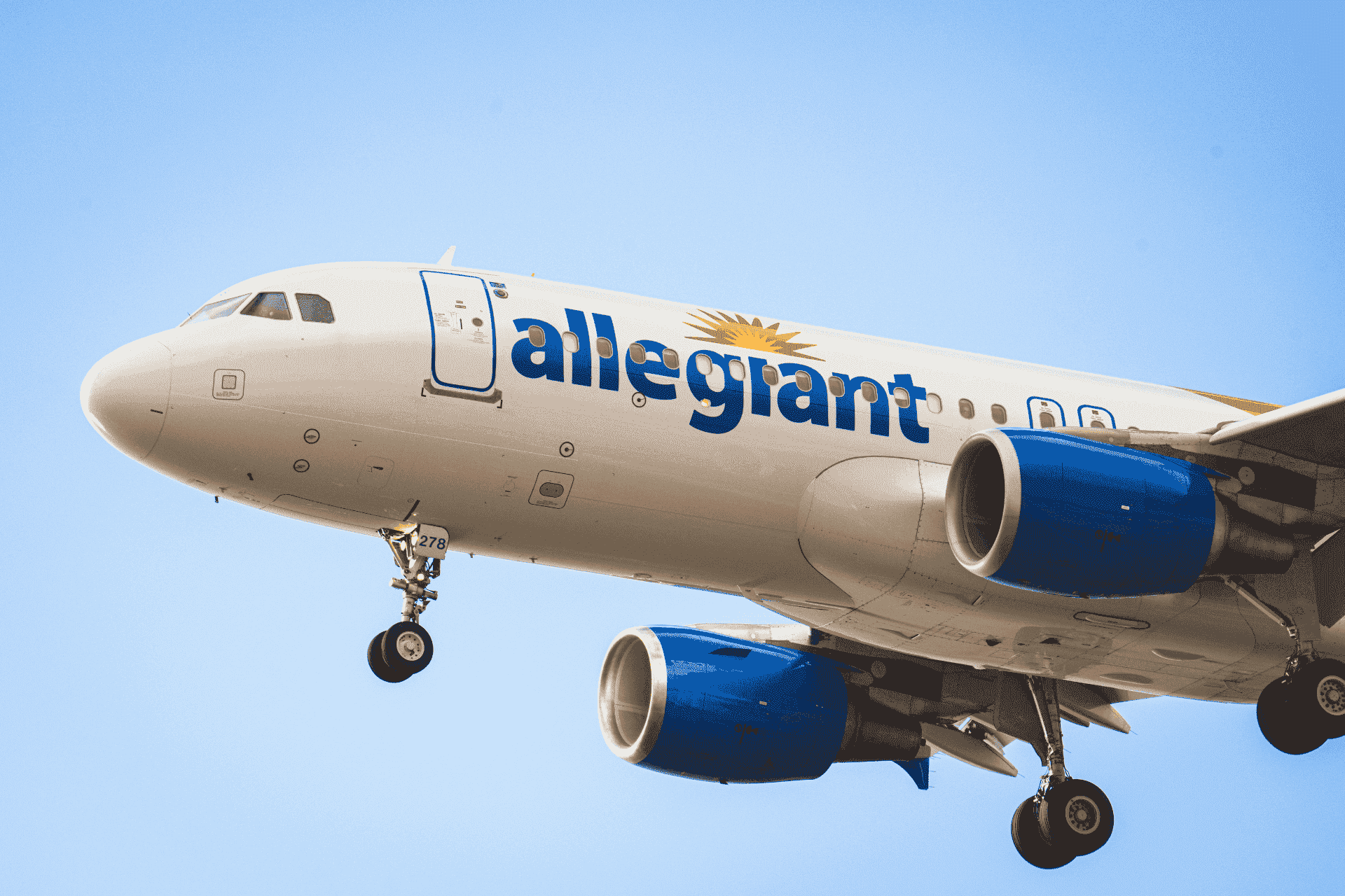 Commercial Allegiant Air airplane flying against a clear blue sky.