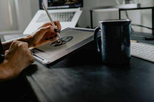 Person sketching design work on a tablet at a desk in a modern studio, representing Cincinnati creative jobs and the changing design industry.