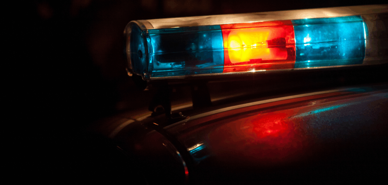 Red and blue police emergency lights illuminated on a cruiser roof at night.