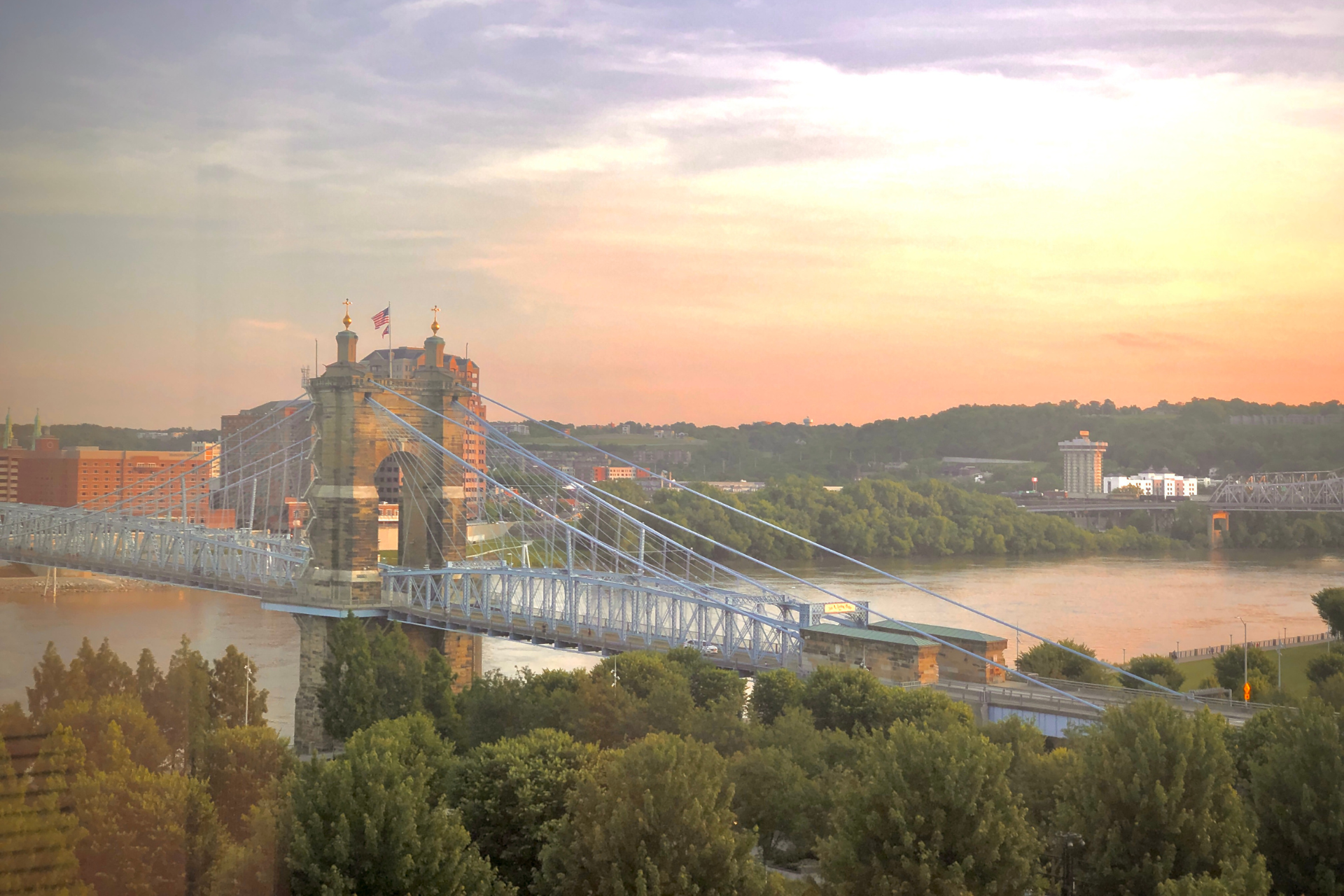 John A. Roebling Suspension Bridge in Cincinnati under a clear sunset sky, representing the city's Thanksgiving weather backdrop.