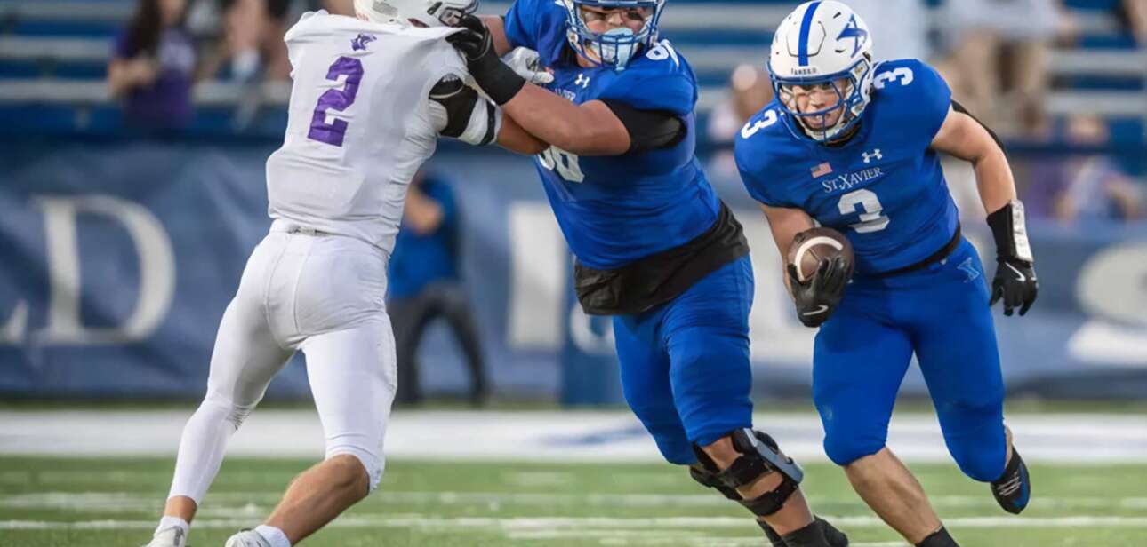 Elder vs St. Xavier football players collide at midfield during a high-intensity play at Paycor Stadium during the 2025 regional championship.