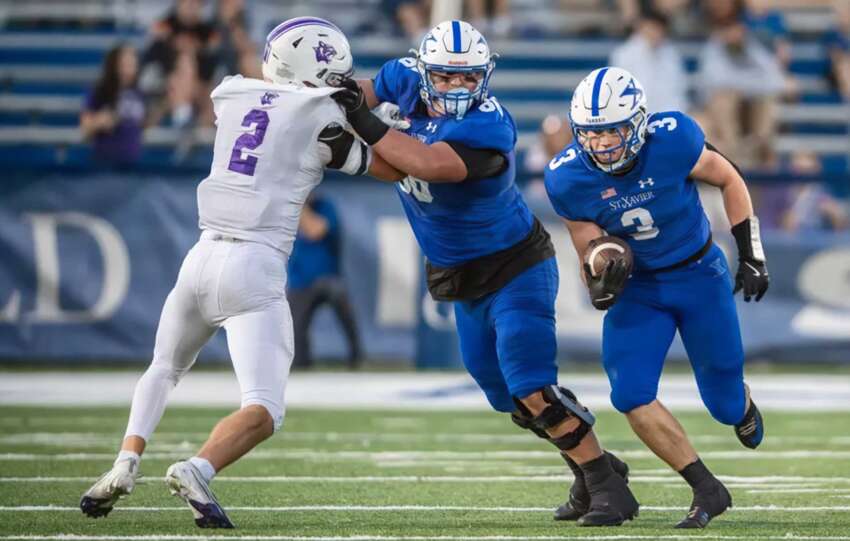 Elder vs St. Xavier football players collide at midfield during a high-intensity play at Paycor Stadium during the 2025 regional championship.