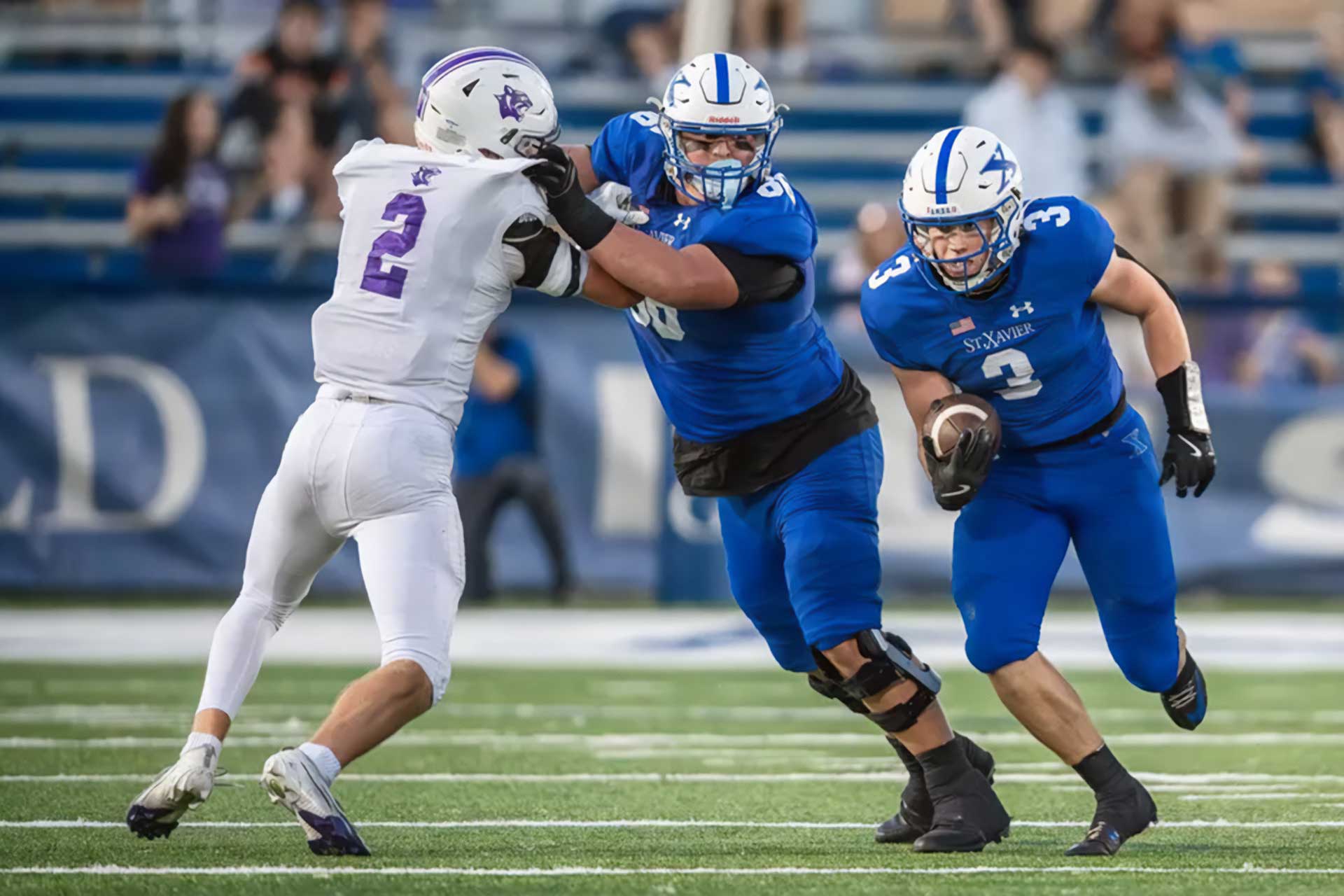 Elder vs St. Xavier football players collide at midfield during a high-intensity play at Paycor Stadium during the 2025 regional championship.