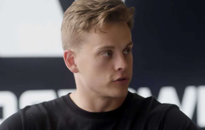 Cincinnati quarterback listening during a press session, highlighting ongoing injury concerns.