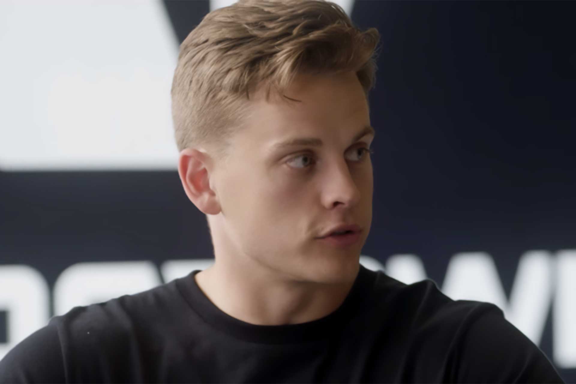 Cincinnati quarterback listening during a press session, highlighting ongoing injury concerns.