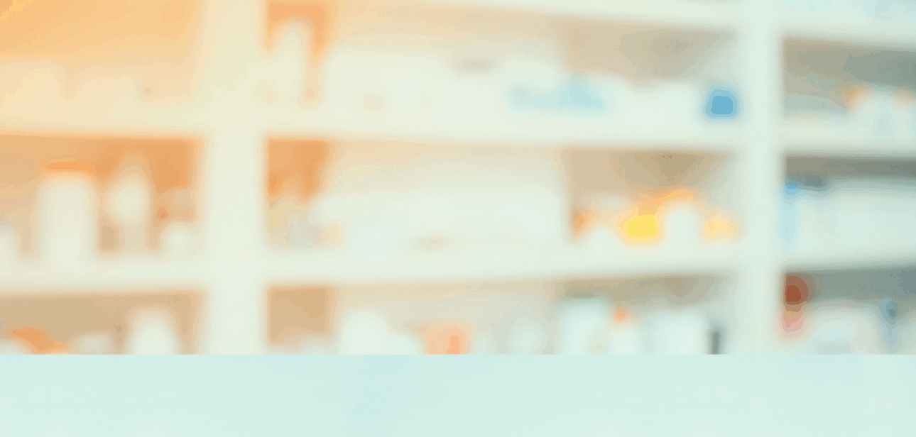 Blurred image of a pharmacy counter with prescription bottles on shelves in the background.