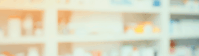 Blurred image of a pharmacy counter with prescription bottles on shelves in the background.