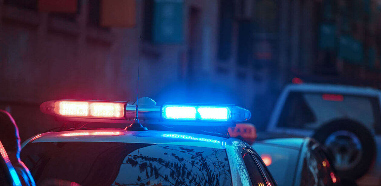 Nighttime police response with patrol cars and flashing lights on a city street.