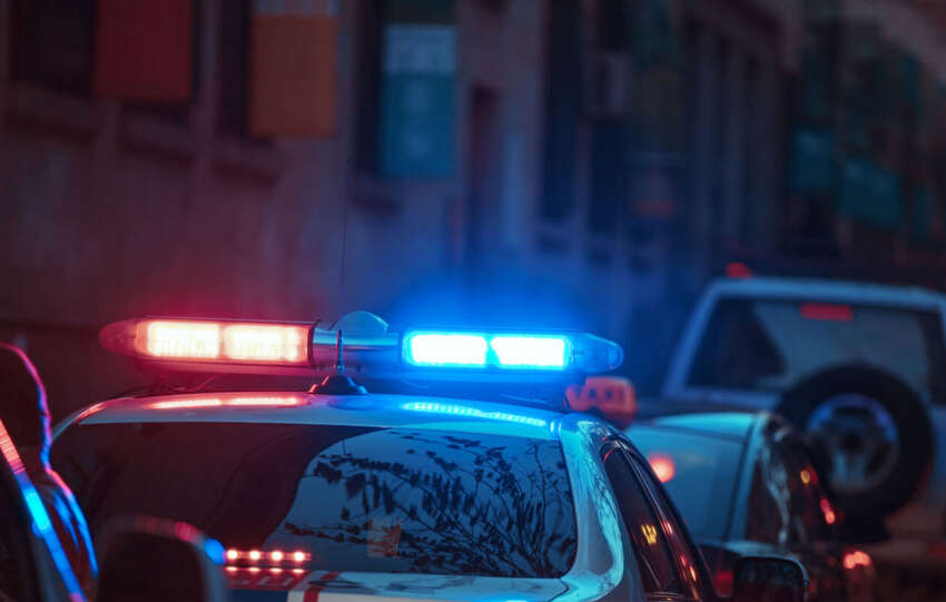 Nighttime police response with patrol cars and flashing lights on a city street.