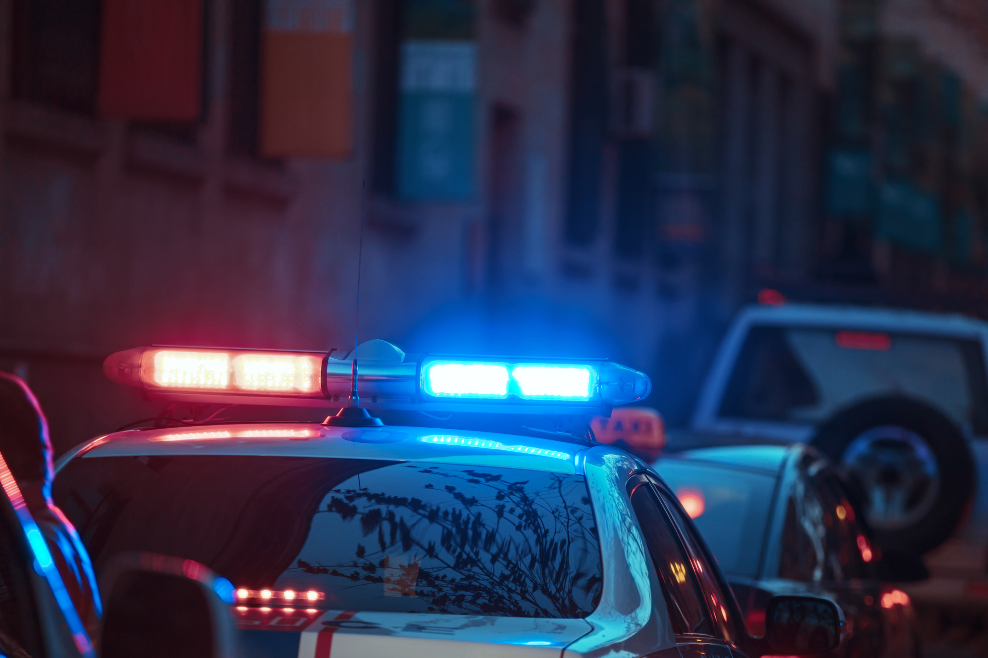 Nighttime police response with patrol cars and flashing lights on a city street.