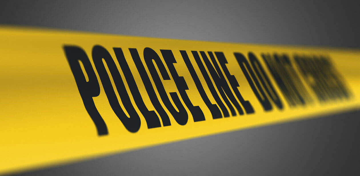 Yellow police tape reading "POLICE LINE DO NOT CROSS" against a dark background, illustrating a crash investigation scene.