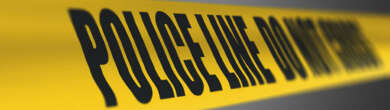 Yellow police tape reading "POLICE LINE DO NOT CROSS" against a dark background, illustrating a crash investigation scene.