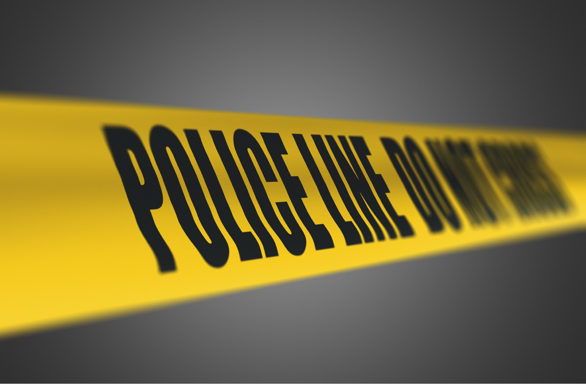 Yellow police tape reading "POLICE LINE DO NOT CROSS" against a dark background, illustrating a crash investigation scene.