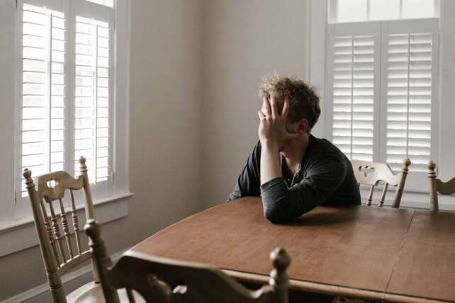 A stressed homeowner sits at a kitchen table in Cincinnati, illustrating the financial strain created by rising property taxes and the push for property tax reform.