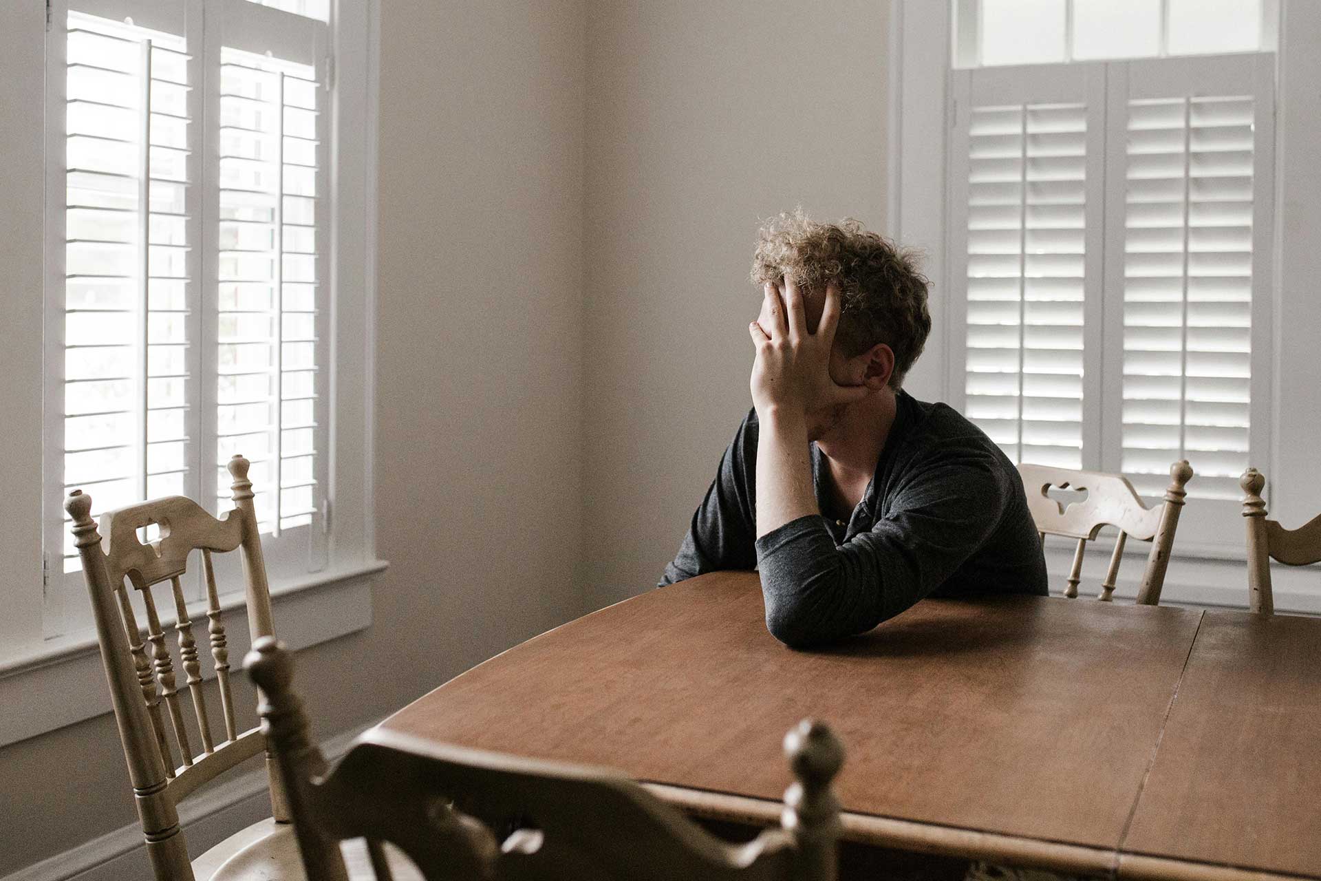 A stressed homeowner sits at a kitchen table in Cincinnati, illustrating the financial strain created by rising property taxes and the push for property tax reform.