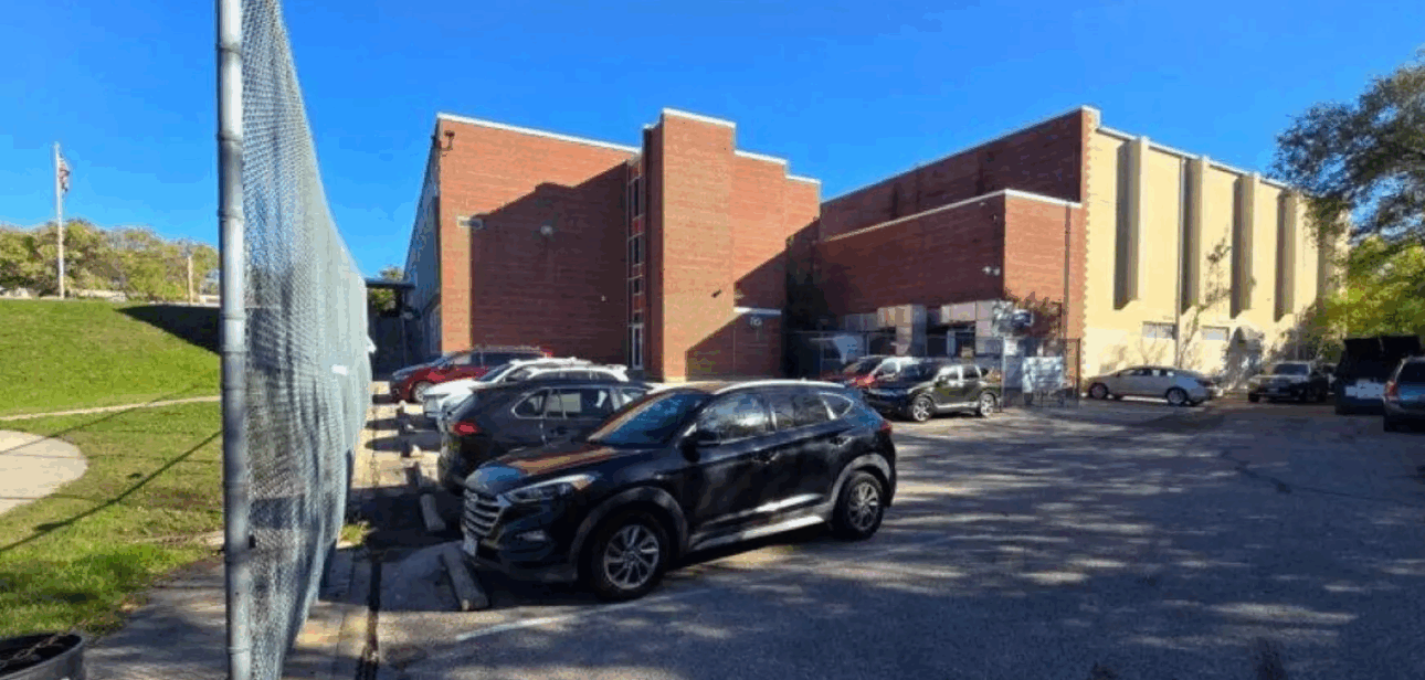 Parking lot beside a Cincinnati Public Schools building with several parked cars on a sunny day.