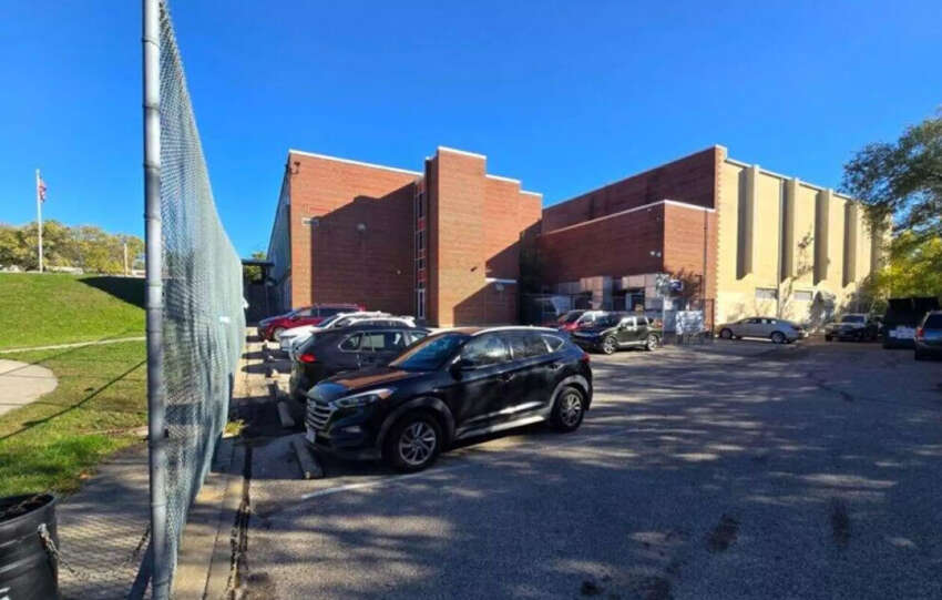 Parking lot beside a Cincinnati Public Schools building with several parked cars on a sunny day.