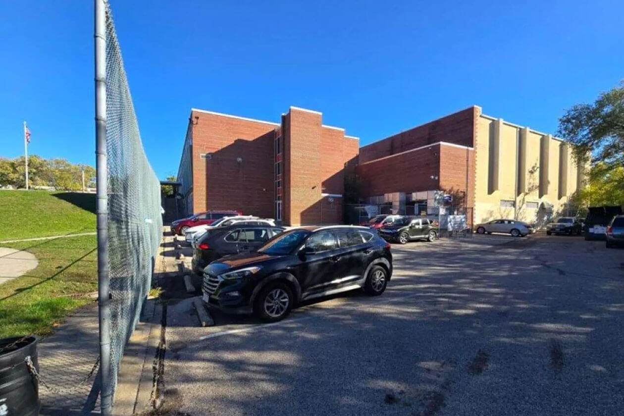 Parking lot beside a Cincinnati Public Schools building with several parked cars on a sunny day.