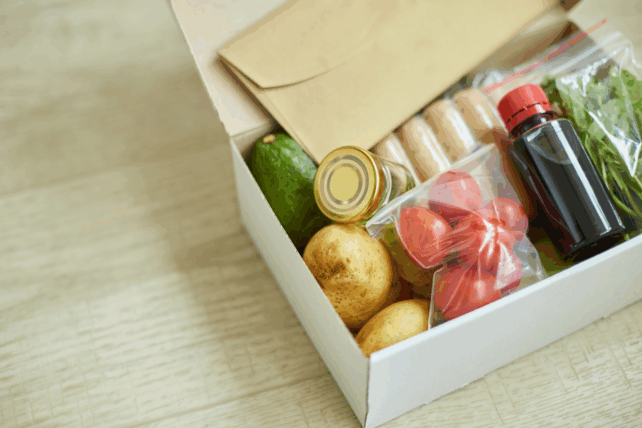 Open Thanksgiving meal kit box filled with fresh potatoes, vegetables, and ingredients for distribution in Greater Cincinnati.