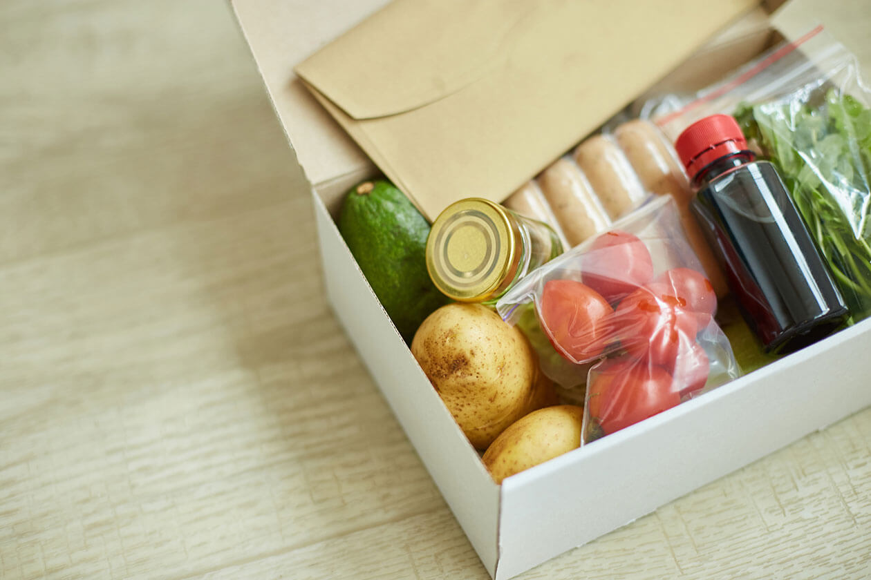 Open Thanksgiving meal kit box filled with fresh potatoes, vegetables, and ingredients for distribution in Greater Cincinnati.