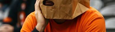 Dejected Cincinnati Bengals fan wearing a paper bag over their head after a loss, sitting in the stadium looking disappointed.
