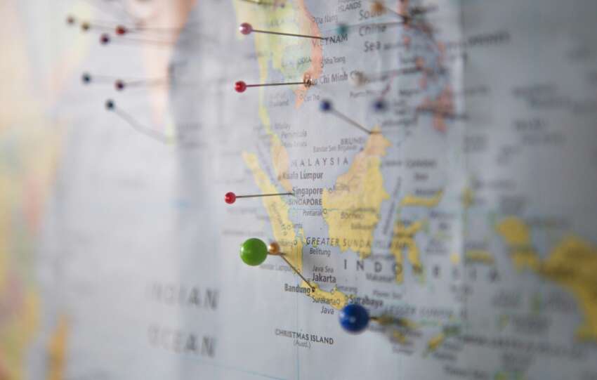 Illustrated world map with colorful push pins marking multiple travel destinations, representing a 2026 travel bucket list with weekend getaways, mid-length trips, and long adventures.