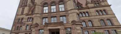 Exterior view of the historic Cincinnati City Hall building featuring red stone architecture and a clock tower.