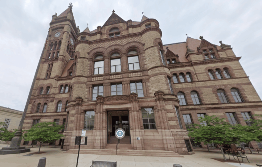 Exterior view of the historic Cincinnati City Hall building featuring red stone architecture and a clock tower.