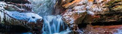 Snow-covered Hocking Hills Cave surrounded by winter forest in Ohio