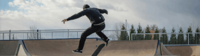 Skateboarder performing a mid-air trick over a ramp that will be soon be seen at Camp Washington Skate Park in Cincinnati under a cloudy sky.