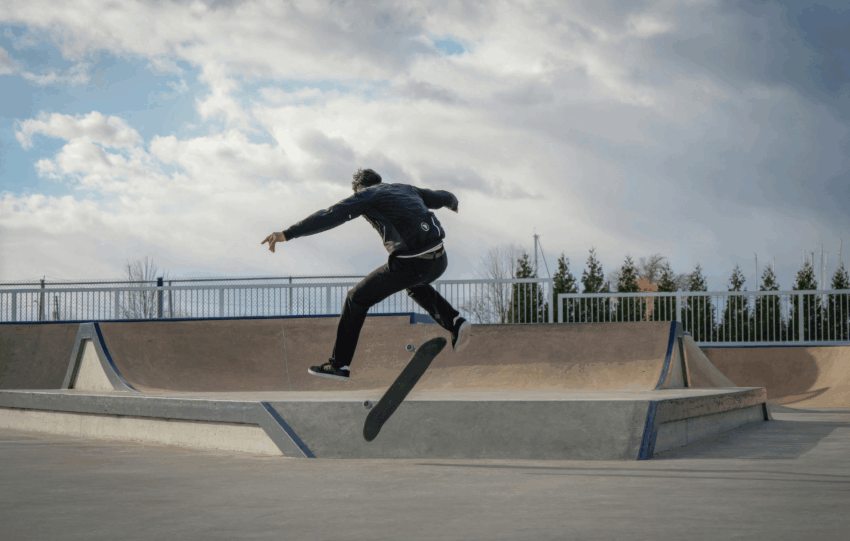 Skateboarder performing a mid-air trick over a ramp that will be soon be seen at Camp Washington Skate Park in Cincinnati under a cloudy sky.