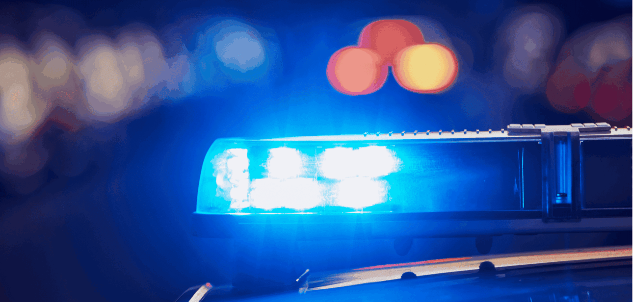 Close-up of blue police emergency lights flashing against a dark background.