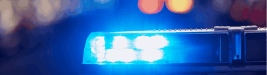Close-up of blue police emergency lights flashing against a dark background.