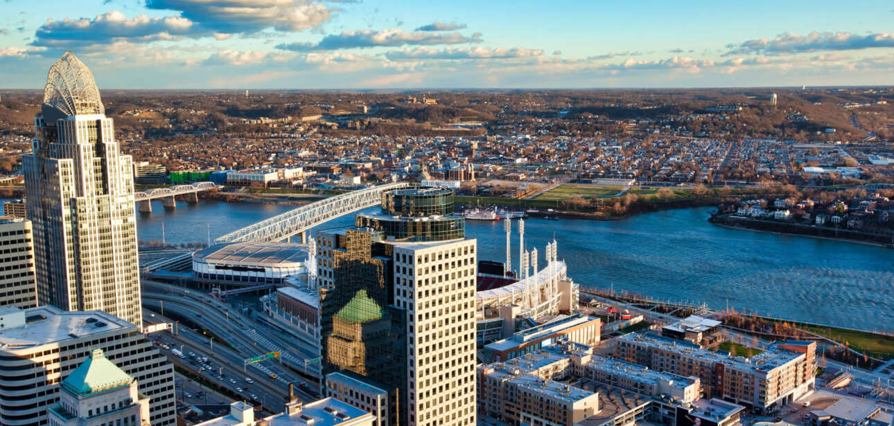 Aerial view of the Cincinnati, Ohio skyline featuring the Roebling Suspension Bridge spanning the Ohio River.