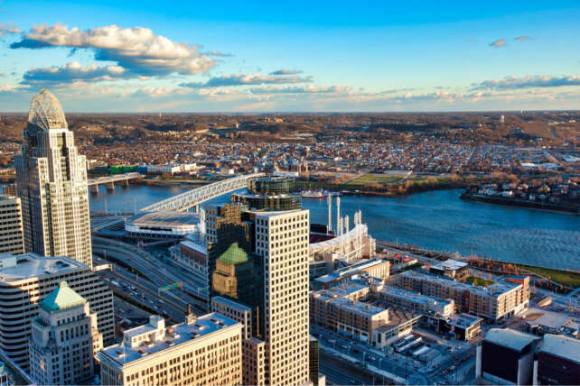 Aerial view of the Cincinnati, Ohio skyline featuring the Roebling Suspension Bridge spanning the Ohio River.