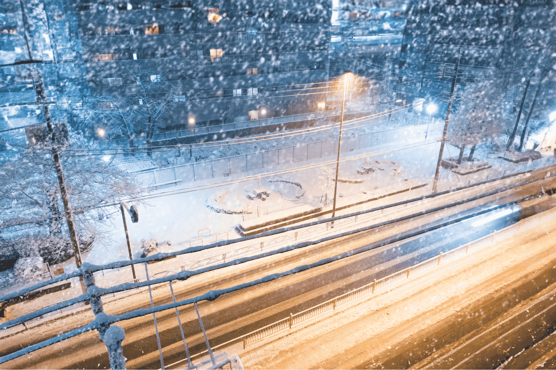Stock image to represent a snow-covered street at night with streetlights and car light trails during a cold weather advisory in Cincinnati.