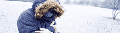 Person that shows bundling up in a heavy winter coat with a fur hood during freezing snowy weather in Cincinnati.