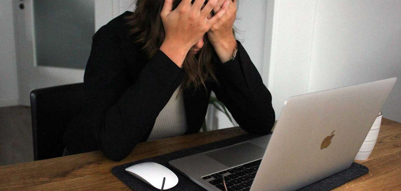 A woman sitting at a desk with her head in her hands, representing frustration and concern about Cincinnati community accountability.