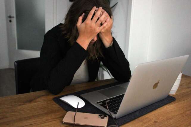 A woman sitting at a desk with her head in her hands, representing frustration and concern about Cincinnati community accountability.