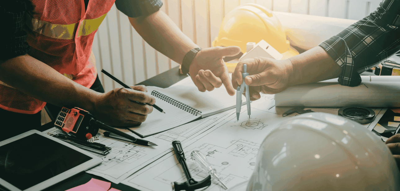 Construction workers in high-vis vests reviewing blueprints, illustrating the growth of Cincinnati job security in the 2025 construction sector.