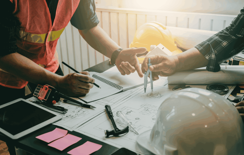 Construction workers in high-vis vests reviewing blueprints, illustrating the growth of Cincinnati job security in the 2025 construction sector.