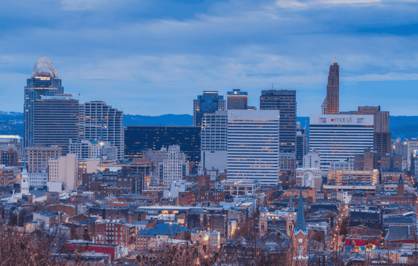 Cincinnati skyline at dusk, featuring the downtown buildings and the Ohio River.
