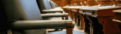 Empty wooden chairs and microphones at the desks illustrating the picture inside the Cincinnati City Council chambers.