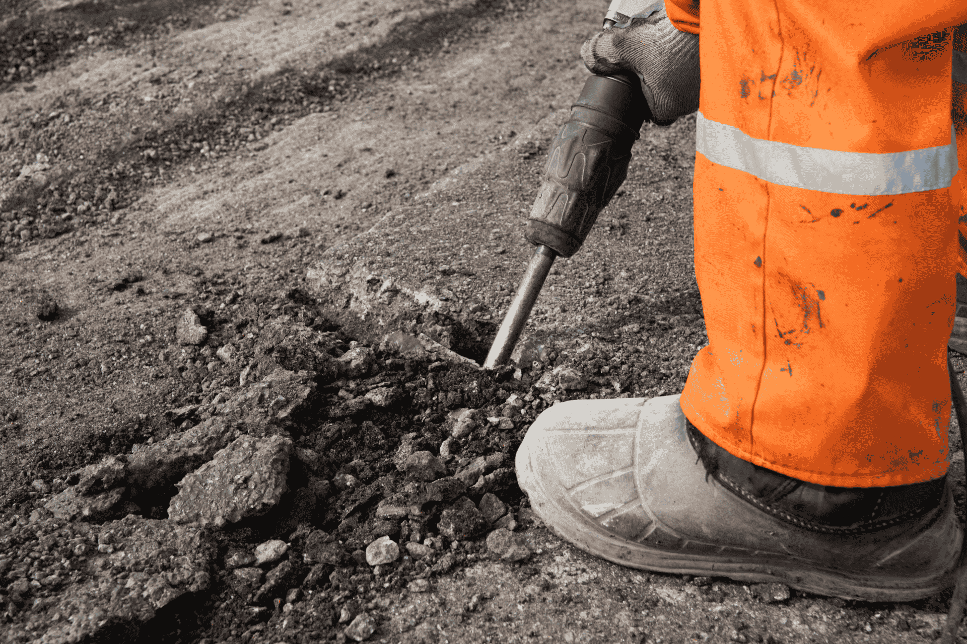 Construction worker using a jackhammer on damaged pavement, representing Cincinnati street repair funds projects.