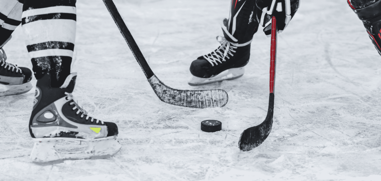 Close-up of ice hockey players' skates and sticks on the ice, illustrating the Cincinnati Cyclones player strike news.