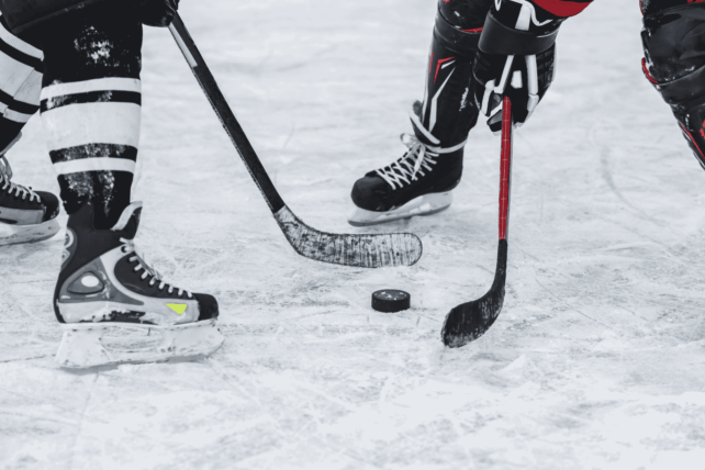 Close-up of ice hockey players' skates and sticks on the ice, illustrating the Cincinnati Cyclones player strike news.
