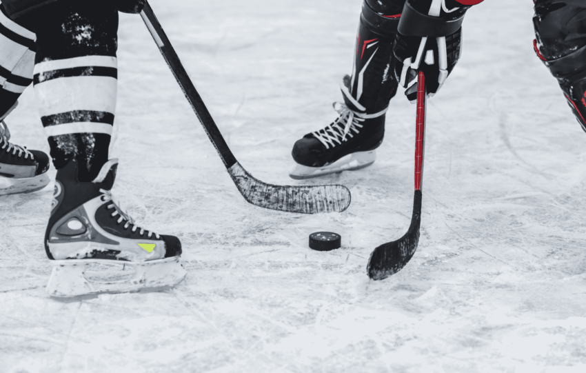 Close-up of ice hockey players' skates and sticks on the ice, illustrating the Cincinnati Cyclones player strike news.