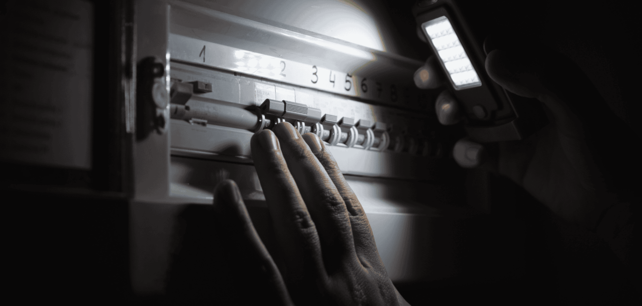 Person shining a flashlight on a circuit breaker panel during a FirstEnergy power outage in Ohio.